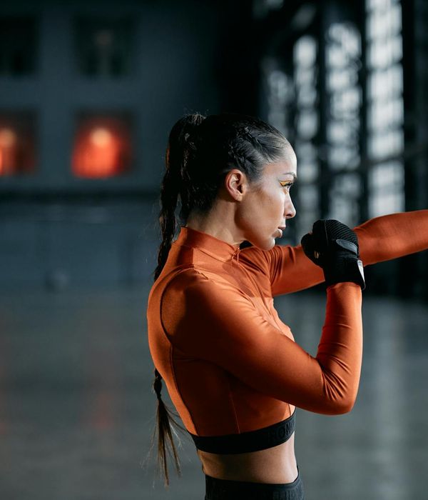 Woman performing a dynamic cardio exercise in a bright studio.